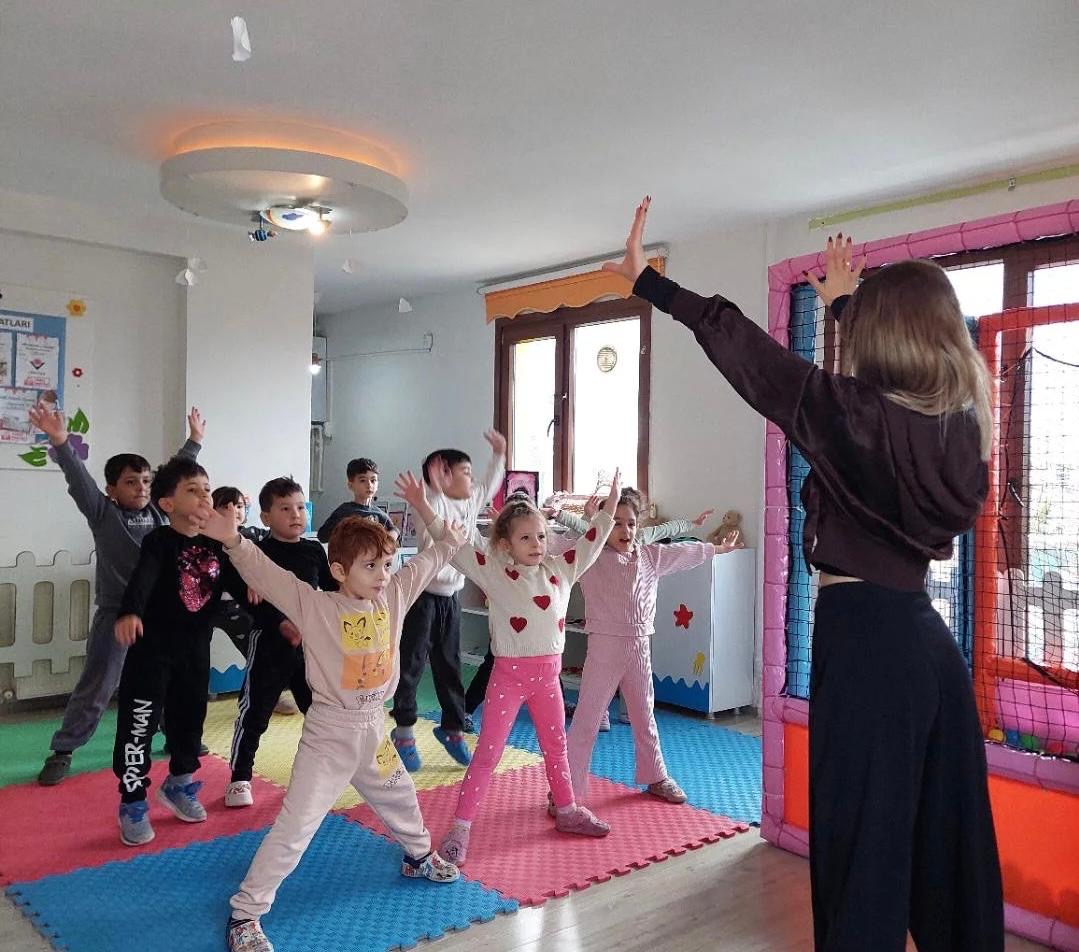 Öğretmen rehberliğinde kollar yukarıda dans figürü